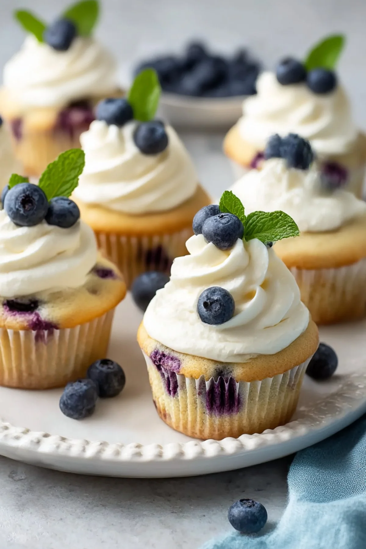Blueberry cream cupcakes with frosting in a decorative display.
