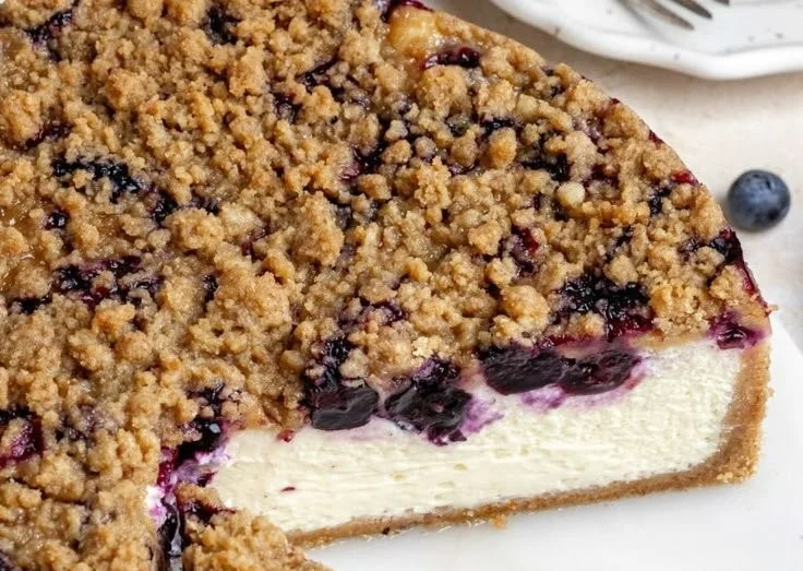 Delicious blueberry cheesecake topped with fresh blueberries and cream.