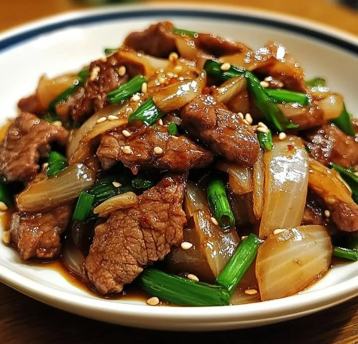 Chinese beef stir fry with onions, chili crisp, and garlic sauce in a serving dish.