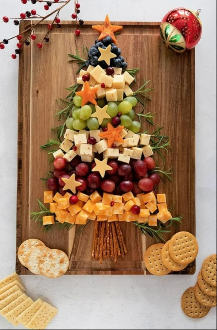 Christmas tree-shaped charcuterie board decorated with festive ingredients