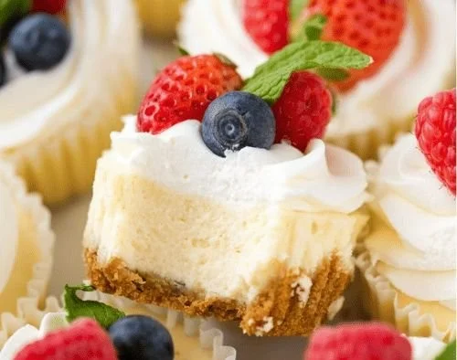 Delicious mini cheesecakes topped with berries and whipped cream.