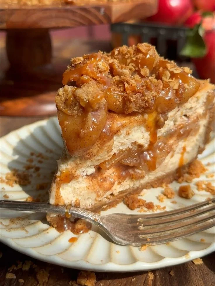 Slice of salted caramel apple pie cheesecake with apples and caramel drizzle