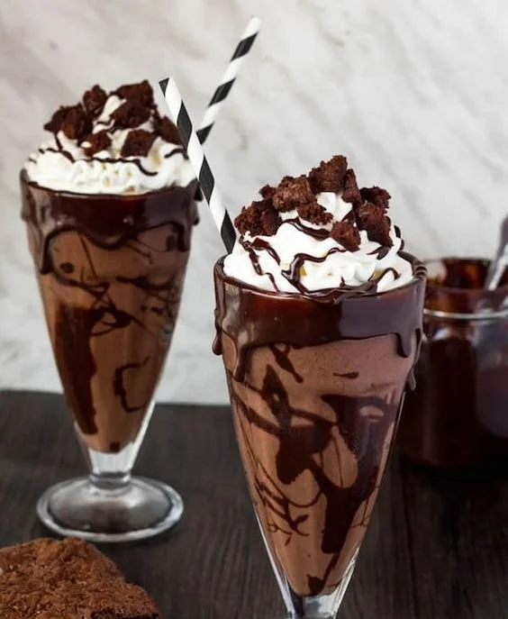 Delicious brownie milkshake topped with whipped cream and chocolate drizzle