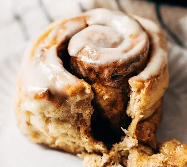 Delicious gluten-free cinnamon rolls topped with icing on a plate.
