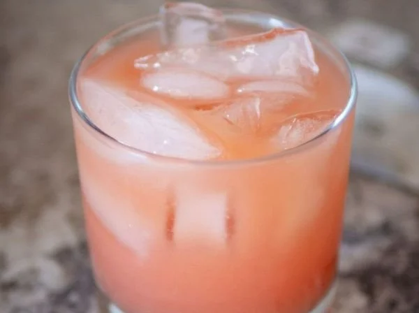 A refreshing glass of Iced Guava White Tea Lemonade garnished with lemon slices.