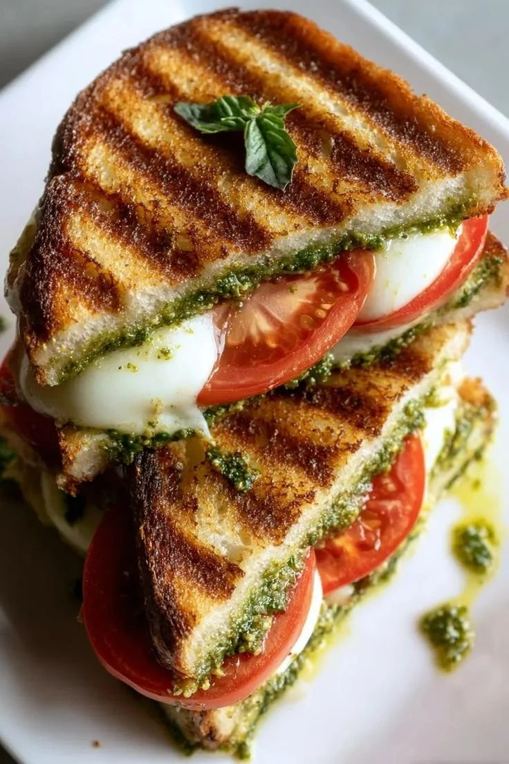 Delicious pesto grilled cheese sandwich on a plate, melted cheese and fresh pesto.
