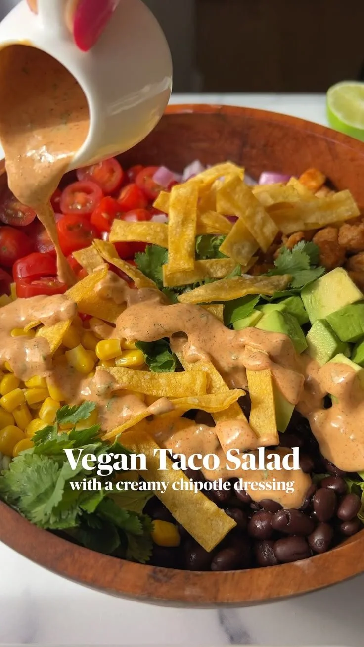 Vegan taco salad topped with creamy chipotle dressing in a colorful bowl