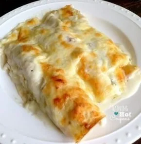 Plate of creamy Chicken Green Chili Enchiladas topped with cheese and green sauce