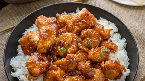 Plate of General Tso's Chicken garnished with sesame seeds and green onions