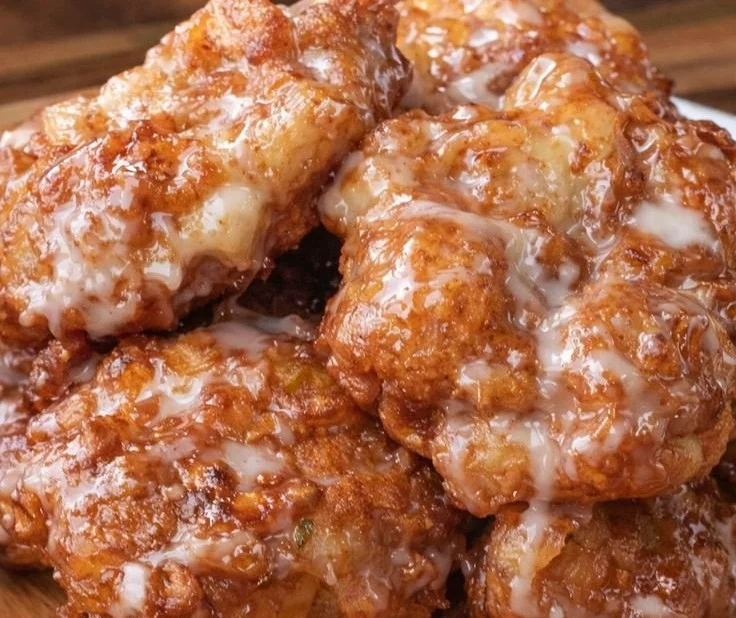 Baked apple fritters on a plate, drizzled with glaze.