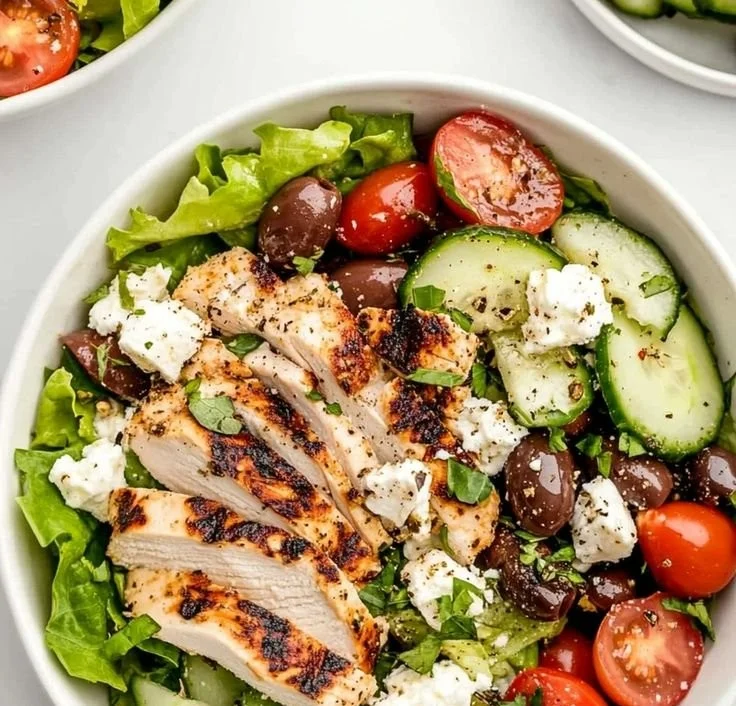 Fresh Greek Salad topped with grilled chicken and vibrant vegetables