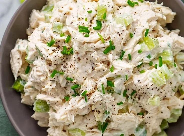 A bowl of simple chicken salad with fresh vegetables and dressing