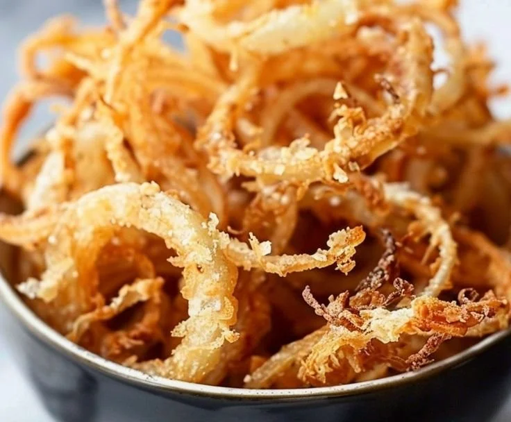 A bowl of air fryer crispy onions, golden and crunchy, perfect as a topping.