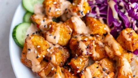 Crispy Bang Bang Tofu served on a plate with sauce and herbs