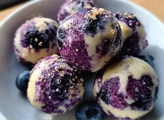 Blueberry cheesecake bites topped with fresh blueberries on a white plate