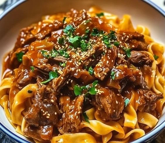 Delicious bowl of Korean beef noodles garnished with fresh herbs and spices.