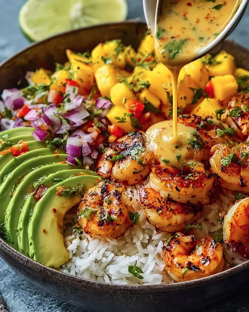 Shrimp avocado bowl with mango salsa and lime-chili sauce on a plate