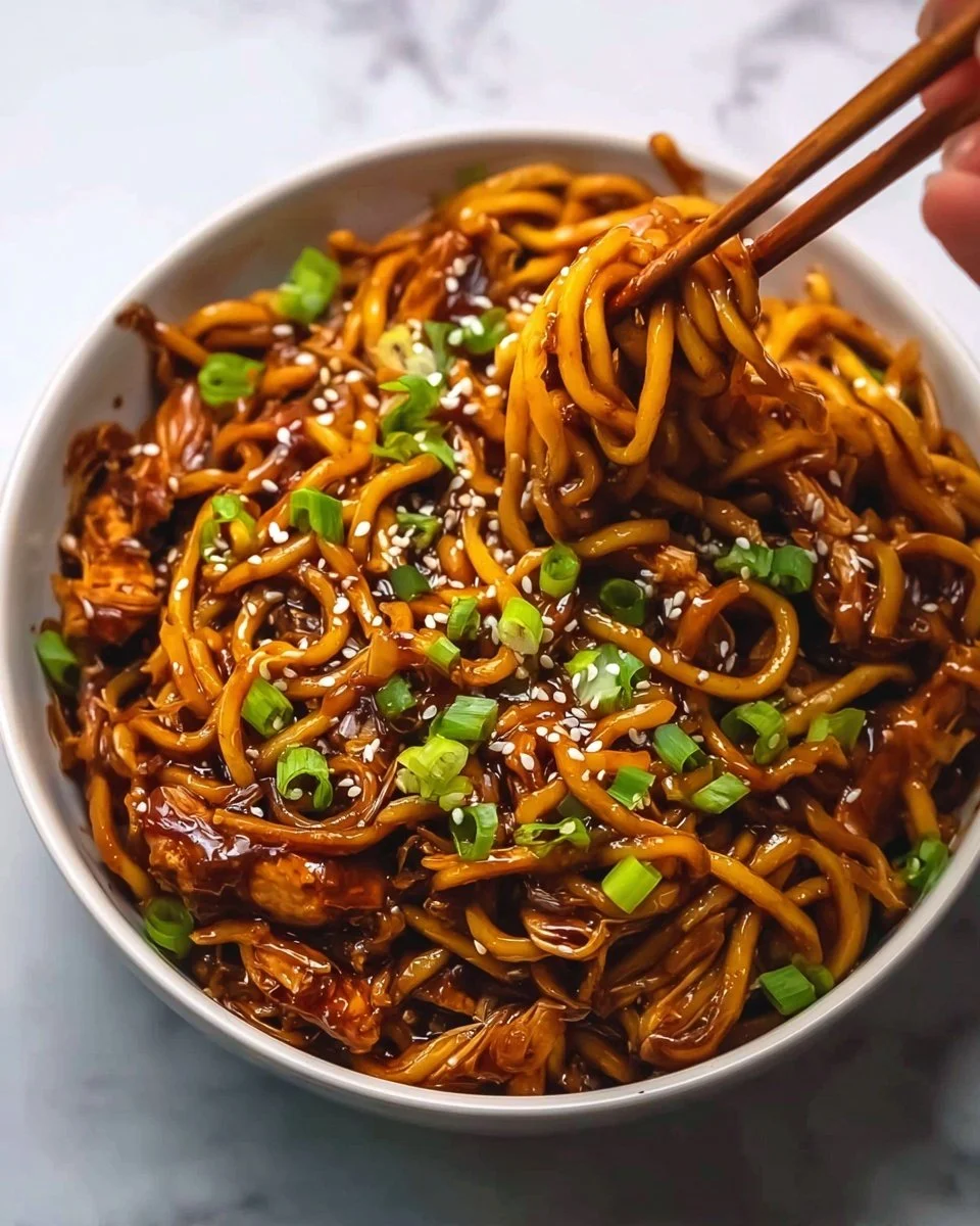 Delicious Sticky Garlic Chicken Noodles on a plate with fresh herbs
