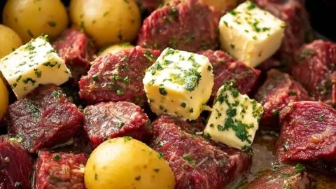 Crock pot garlic butter steak bites served with potatoes on a plate.
